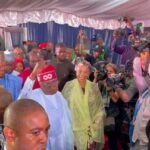 Bola Tinubu gestures at the people crowding around him, after