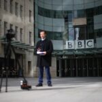 A BBC correspondent reports to a camera outside the BBC